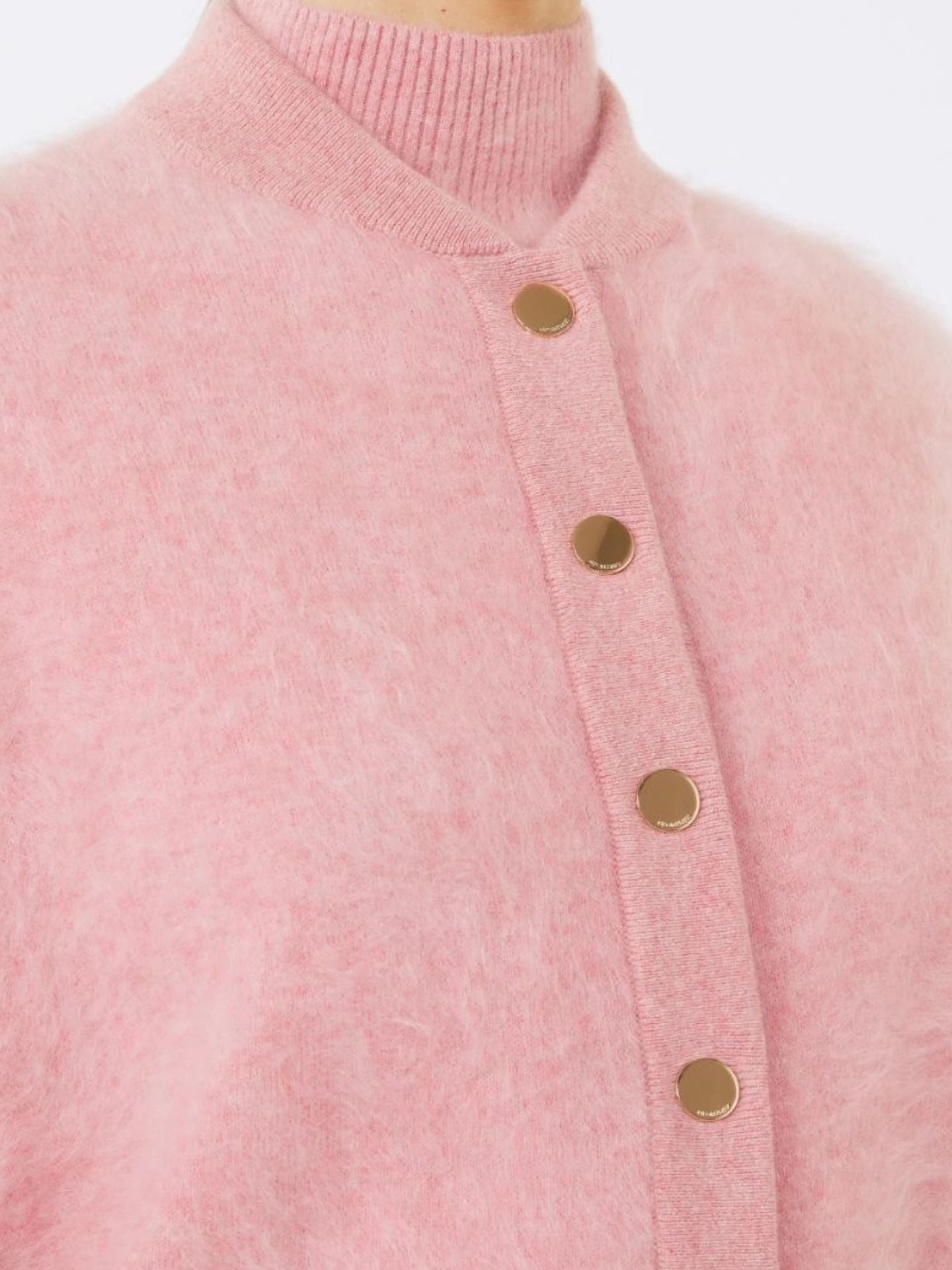 Close-up of a pink cardigan with gold buttons on a white background