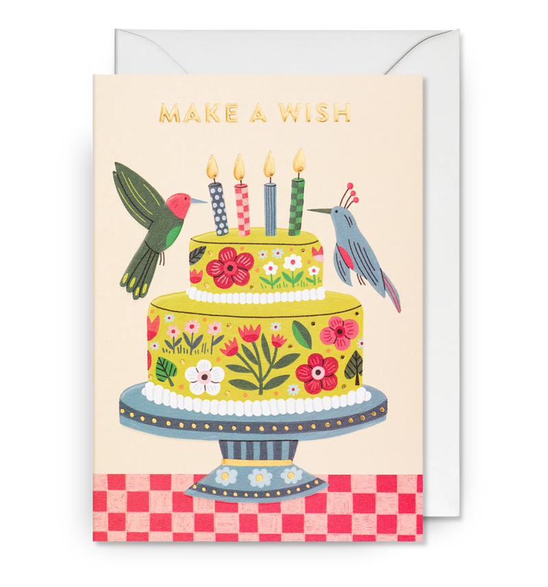 Illustrated birthday cake greeting card with birds, flowers, and 'MAKE A WISH' text on top. The card is shown with its matching envelope.