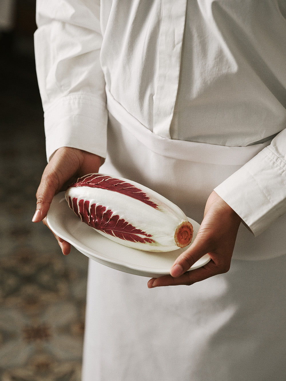 Person holding a plate with a red and white leafy vegetable.