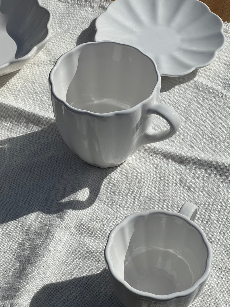 White ceramic cup and saucer on a textured fabric surface