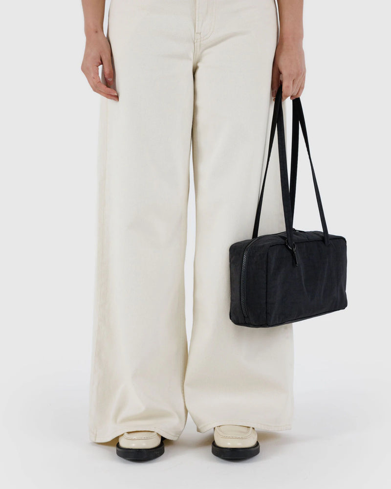 Person holding a black duffel bag against a white background