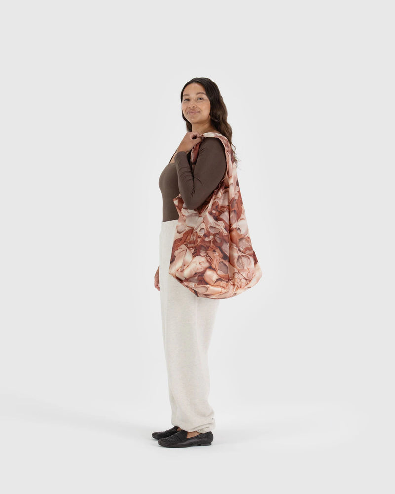 Woman holding a floral-patterned bag against a white background