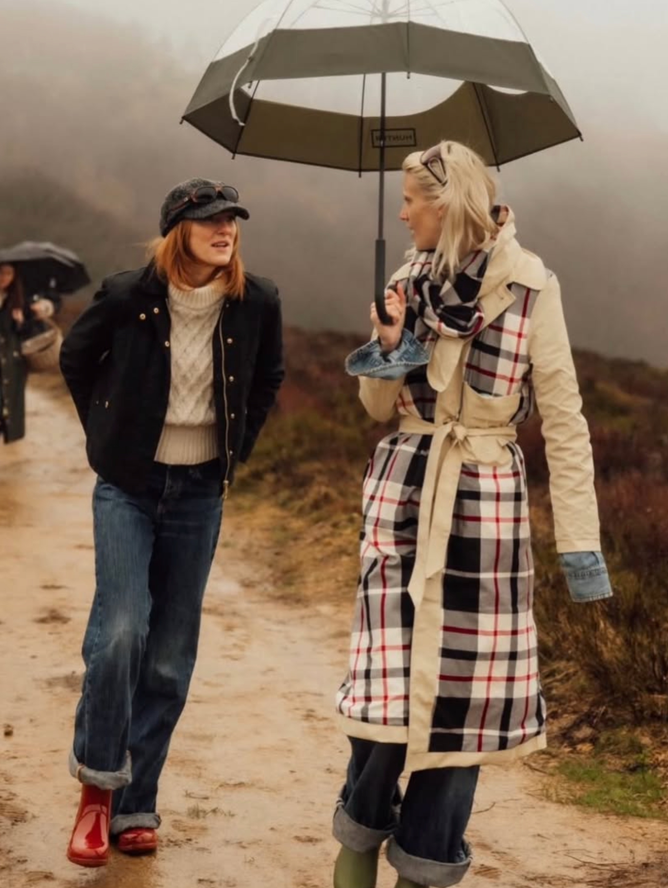Two women walking together on a rainy day, one holding an umbrella.