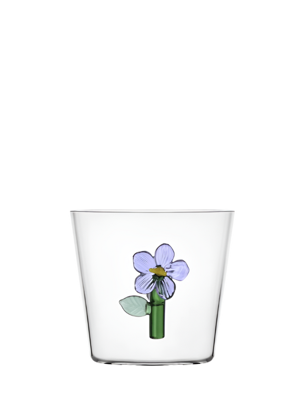 A clear glass tumbler with a green and lilac floral design on the bottom.