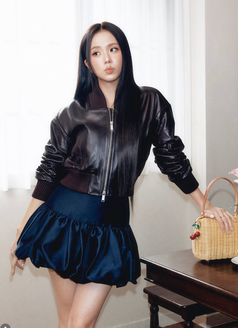 Jisoo wearing a black leather jacket and navy taffeta skirt by Self-Portrait.