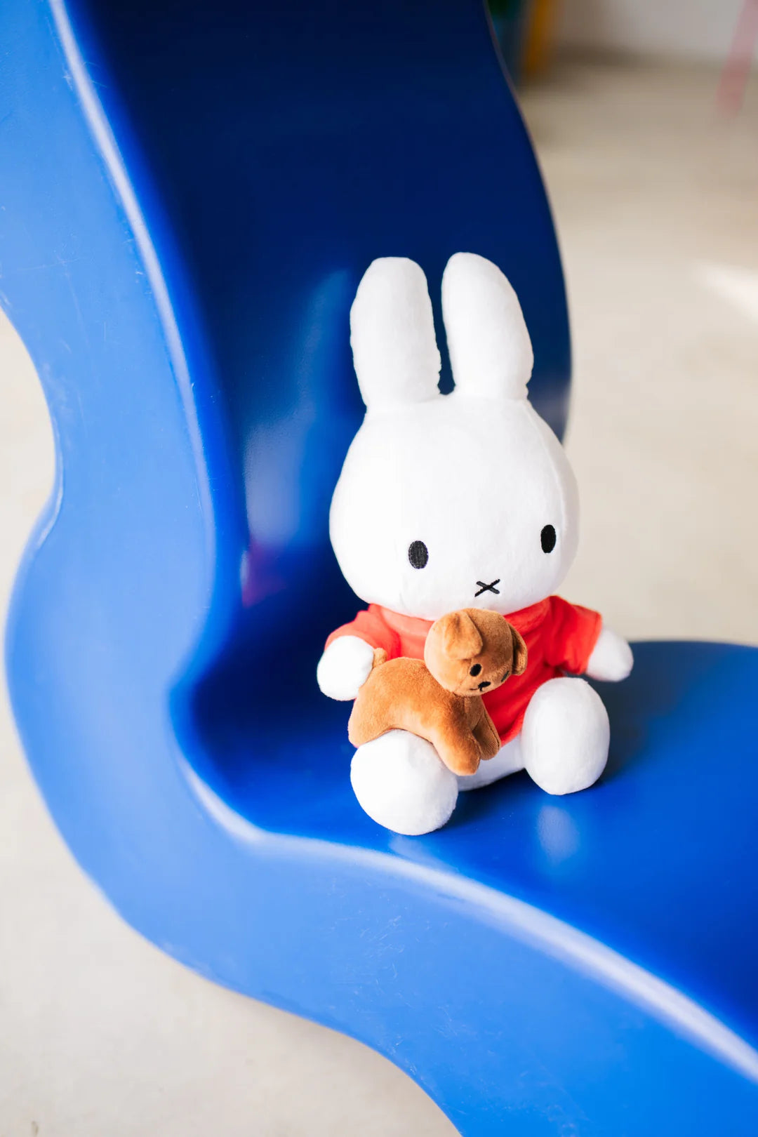White rabbit plush toy with a brown teddy bear on a blue slide