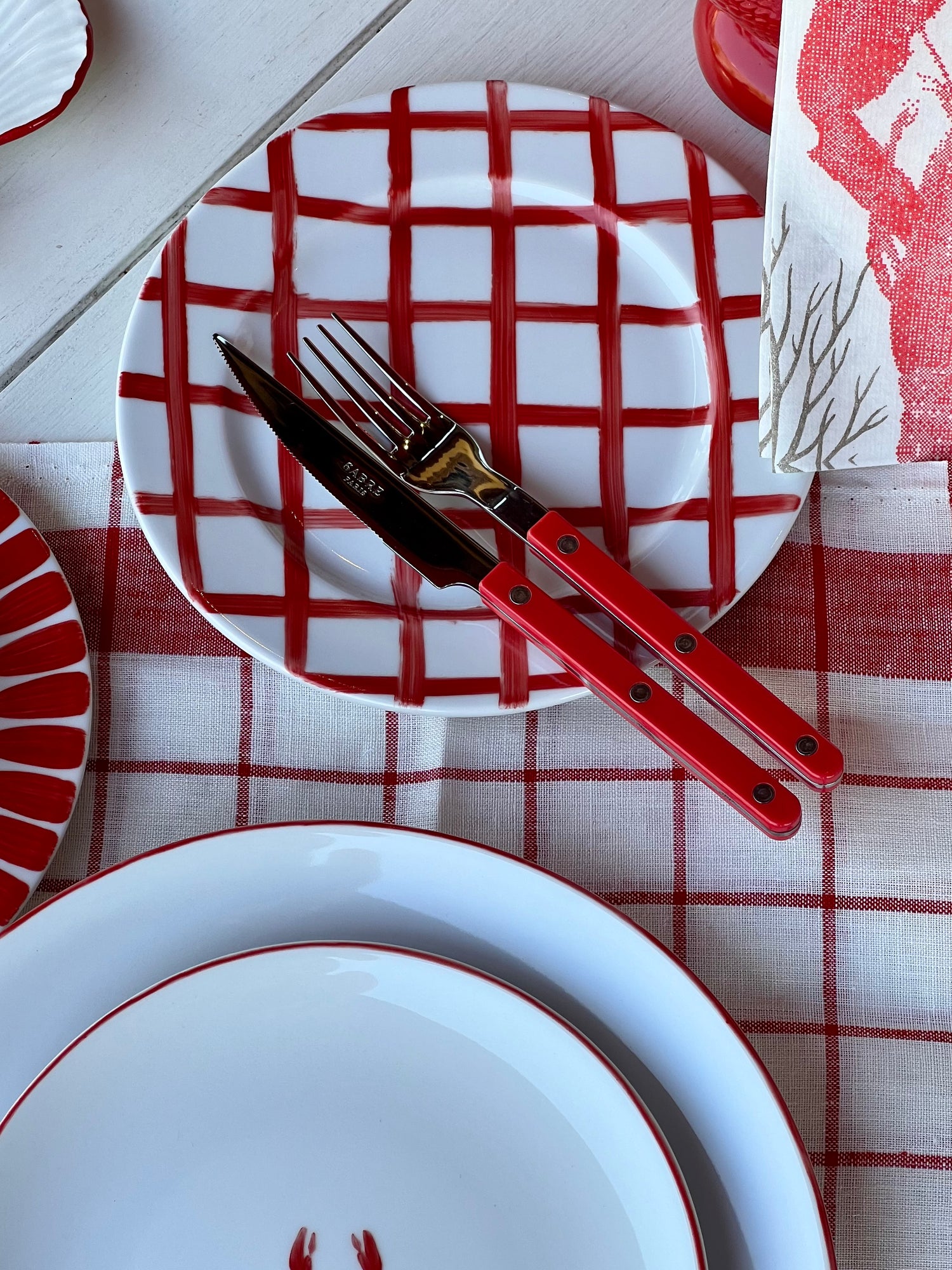 Red and white checkered plates with red cutlery on a matching tablecloth.