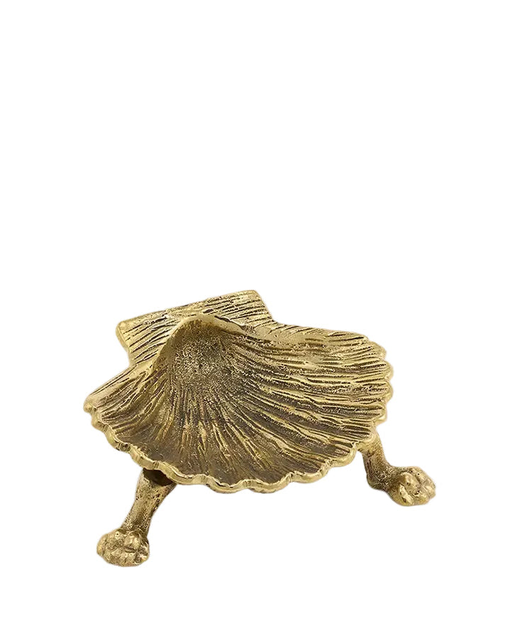 A small shell-shaped decorative object with three legs, finished in a textured metallic gold tone, photographed on a plain light background.