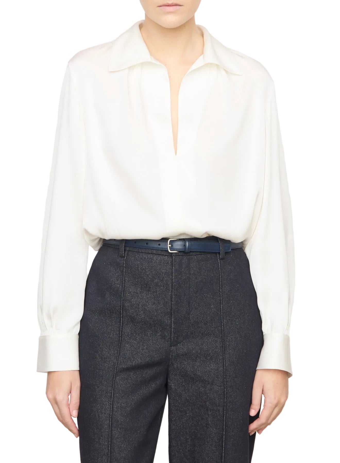 Person wearing a white blouse and dark pants on a plain background