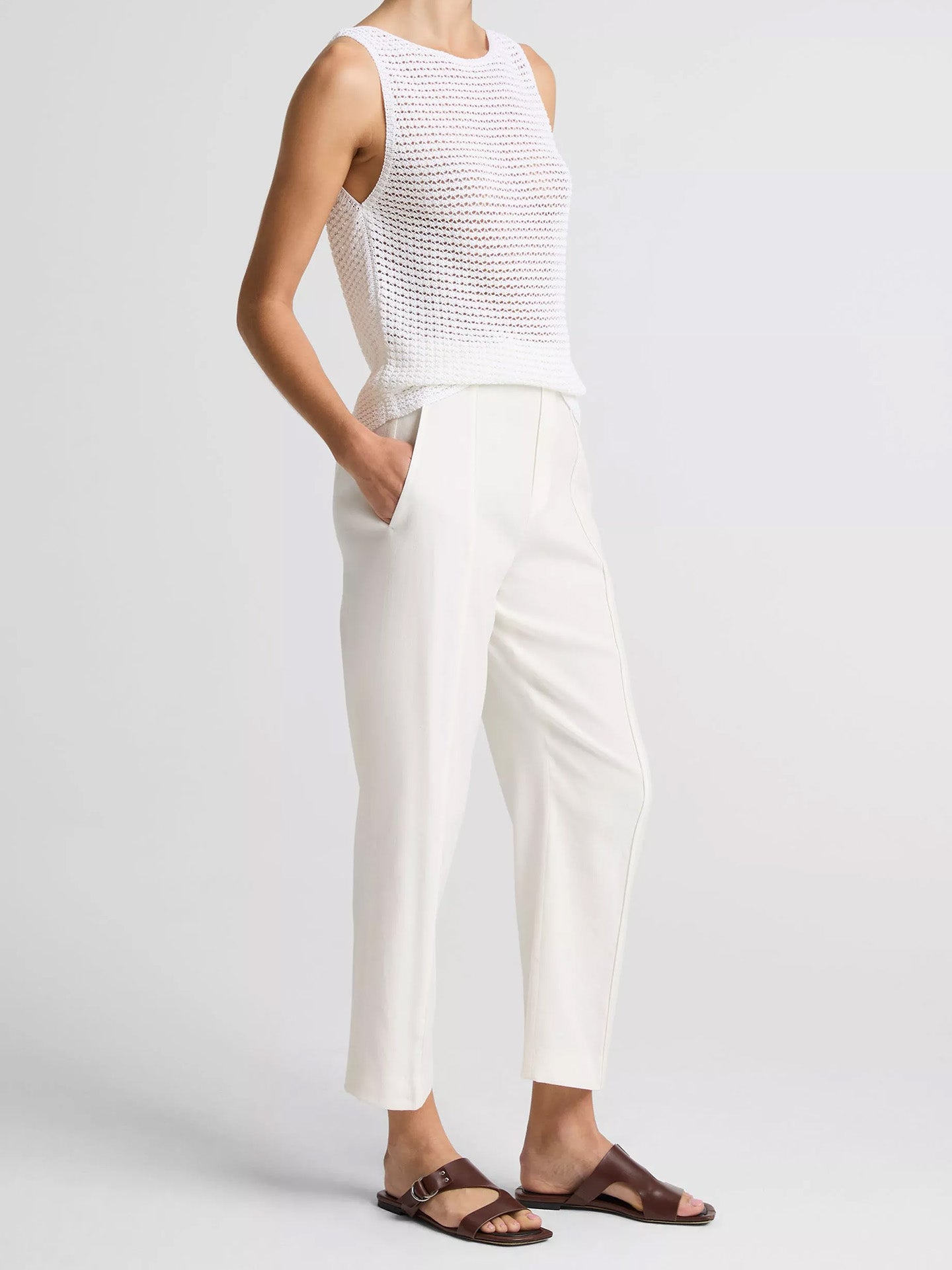 Person wearing a white sleeveless top and pants on a plain background