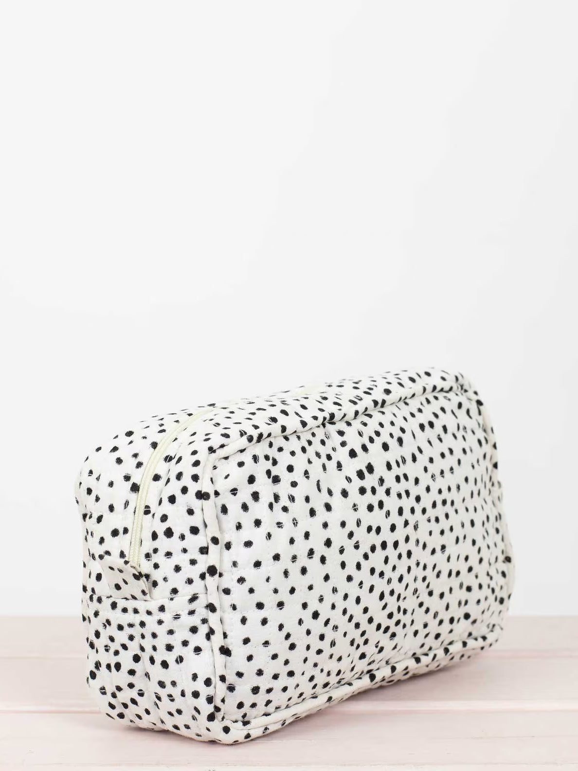 Rectangular pouch with black polka dots on a white background