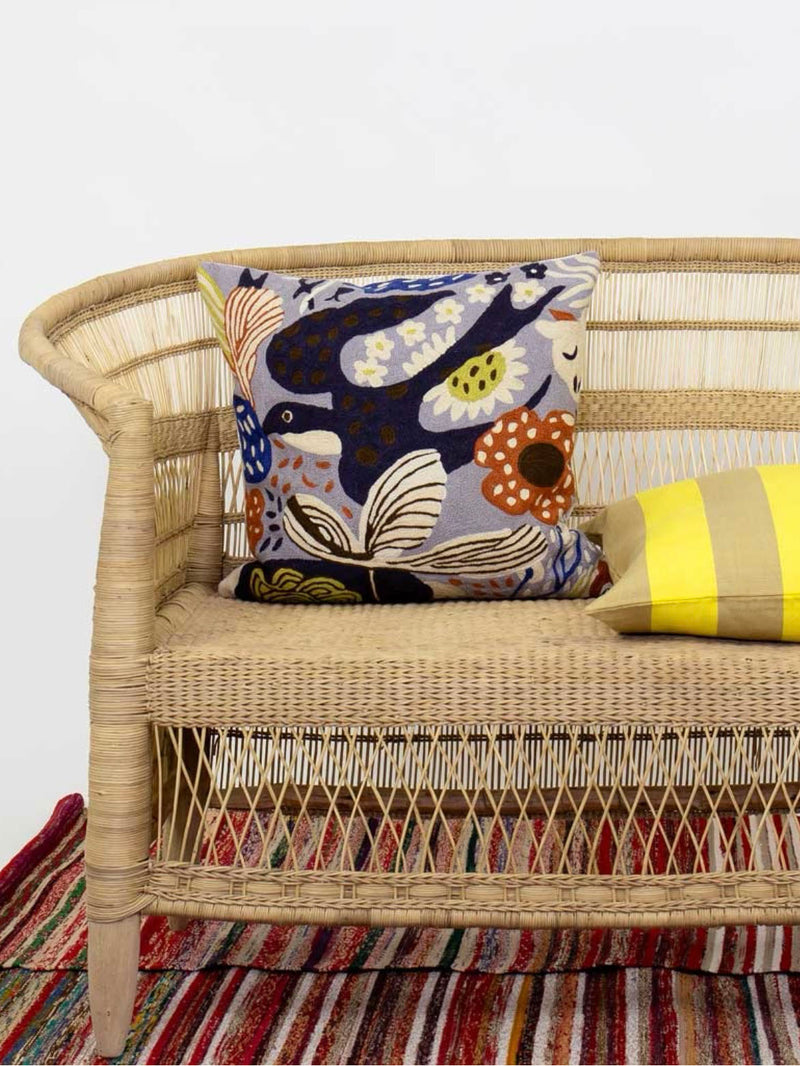 Wicker chair with colorful pillows on a striped rug