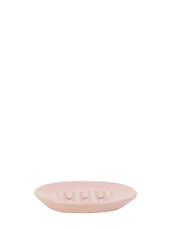 A light pink oval ceramic dish with a textured, ribbed surface and three holes at the center for a soap bar, shown against a solid white background.