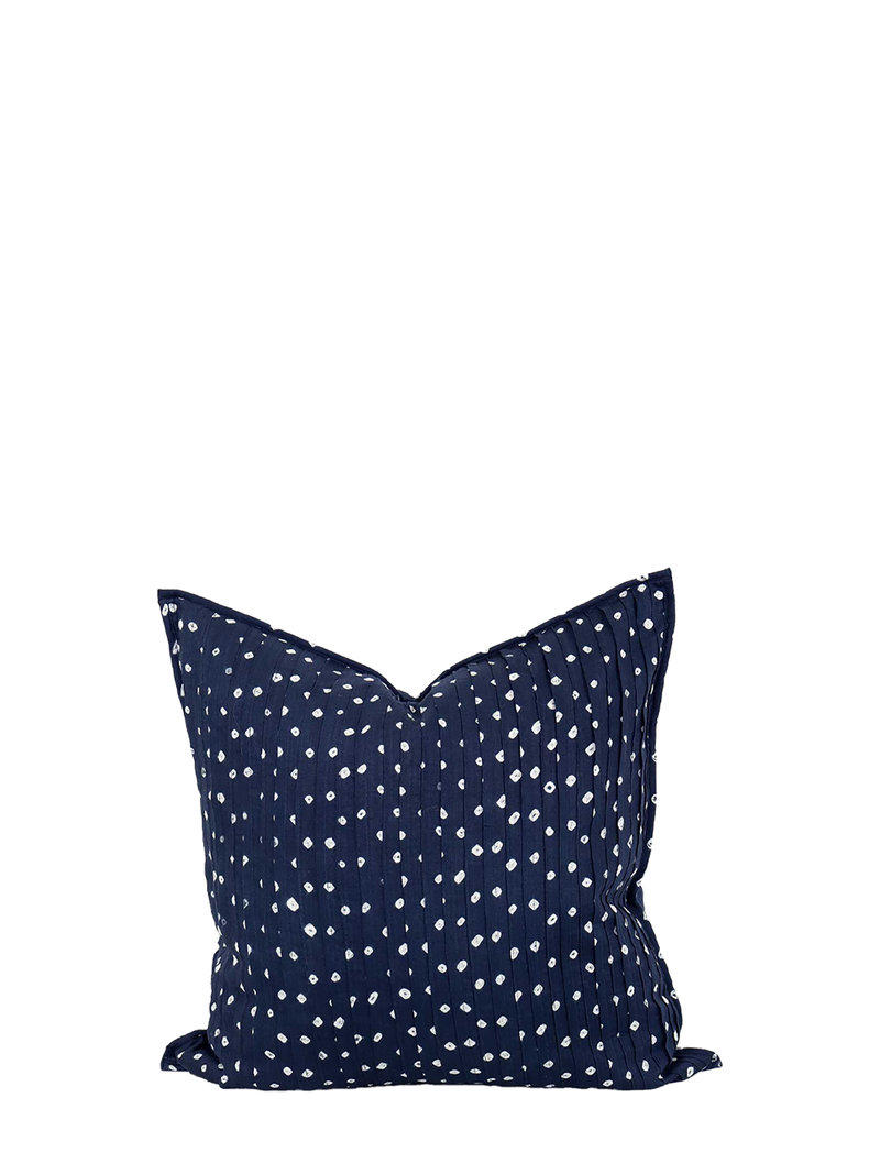 A navy blue cushion cover with white hand-printed dots, crafted from organic cotton.