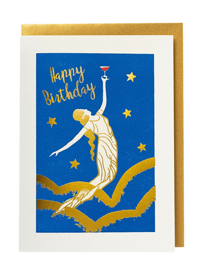 A square birthday card with a white border and a gold envelope behind it. The card depicts a blue background with a gold and white illustration of a woman rising from wavy lines while holding a red cocktail glass, with 'Happy Birthday' written in gold script and a gold envelope behind the greeting card
