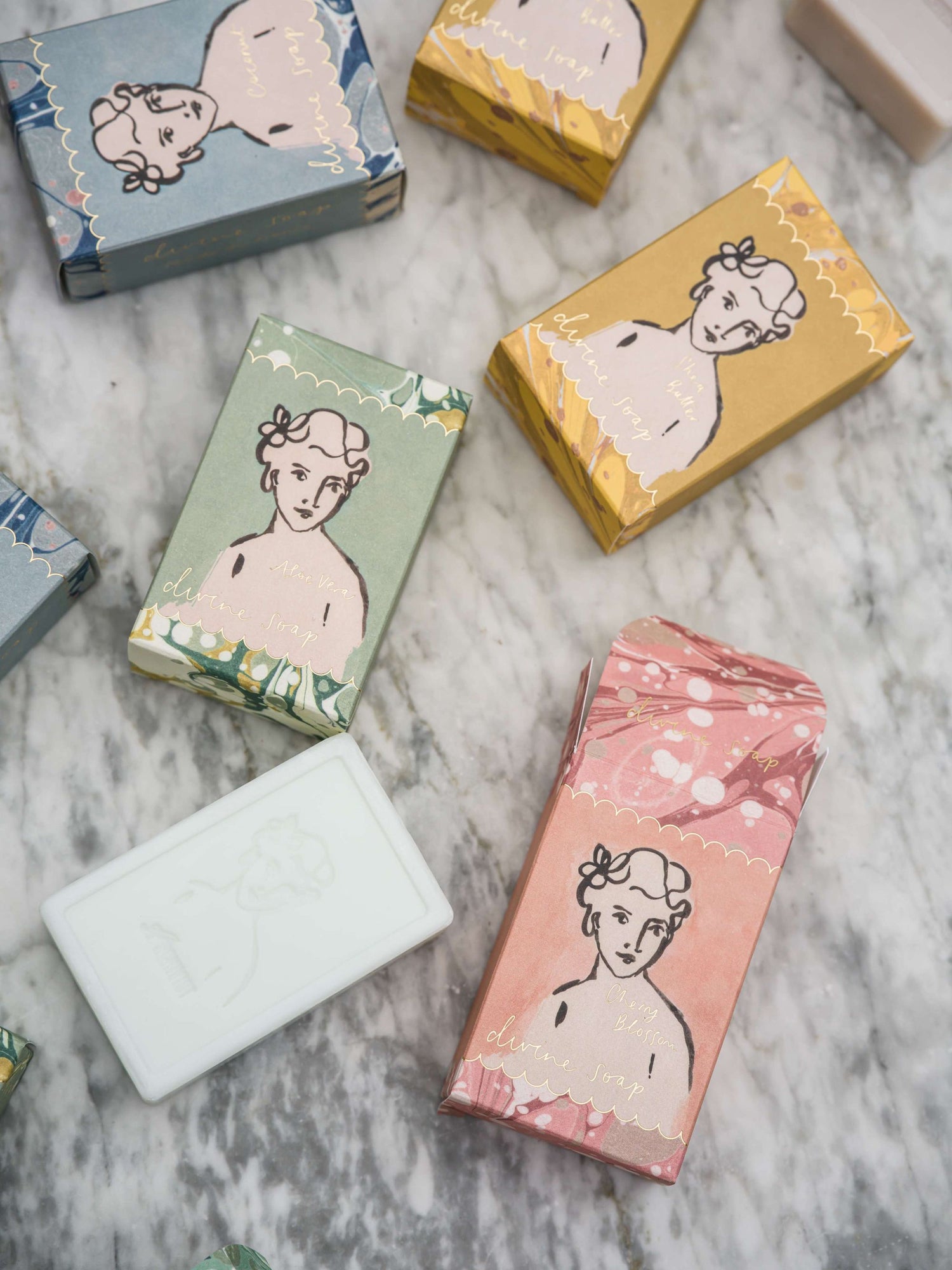 Soap bars with decorative packaging featuring illustrations of women on a marble surface