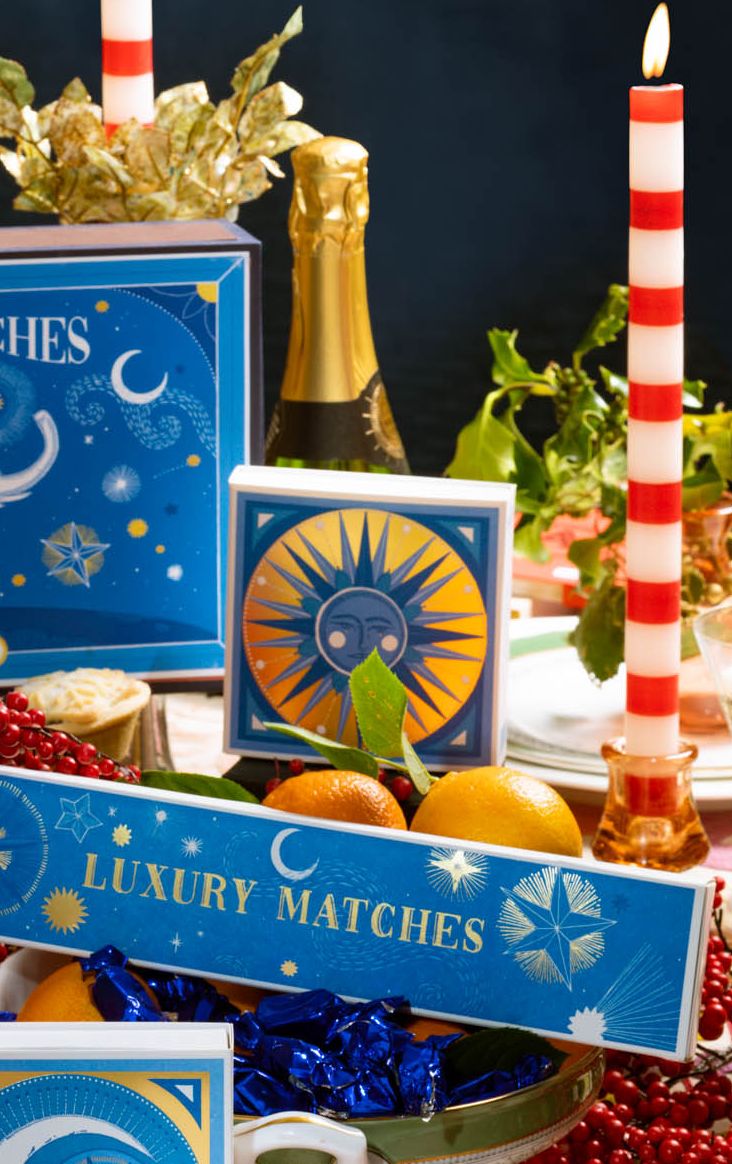 Decorative table setting with candles, fruits, and a sign labeled 'Luxury Matches' on a dark background.