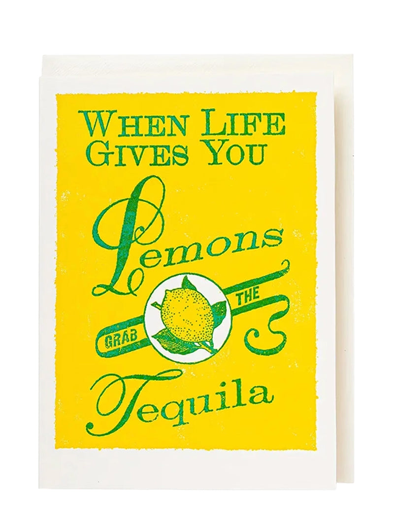 A large greeting card with a bright yellow front featuring green text that reads 'WHEN LIFE GIVES YOU Lemons GRAB THE Tequila' and a lemon illustration, shown with a white envelope behind it on a white background.