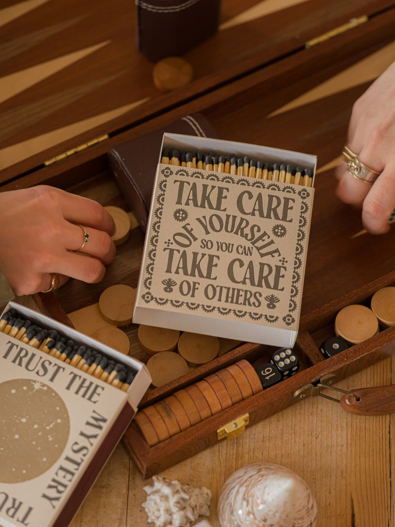 Matchbox with motivational quote on a wooden surface with a backgammon board.