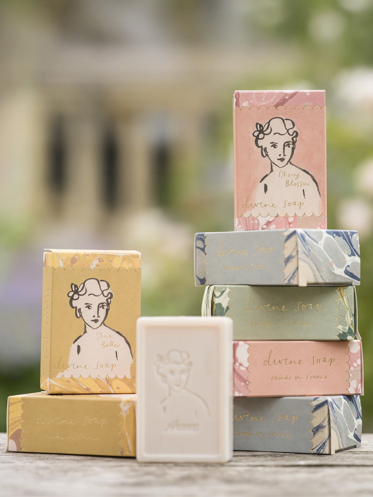 Collection of soap bars with decorative packaging featuring illustrations on a blurred natural background