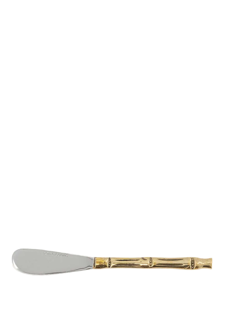 A silver metal spreader or knife with a gold-toned bamboo-style handle, shown horizontally against a solid off-white background.