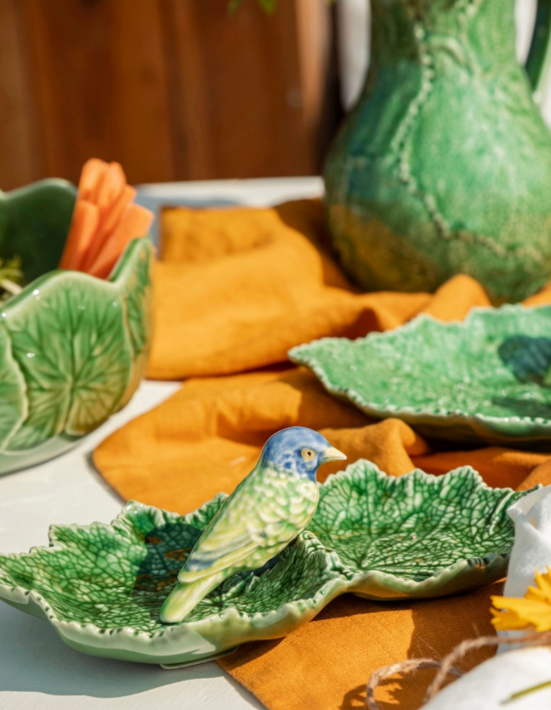 Ceramic bird and leaf dish on a table with green ceramic pitcher and platter.