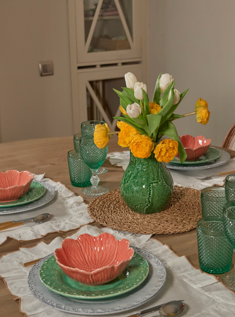 Dining table set with floral centerpiece, plates, and glasses.