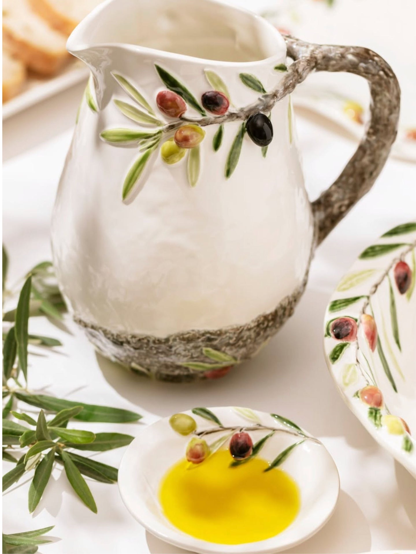 Decorative ceramic pitcher with olive design on a white surface