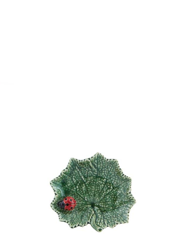 A small green leaf-shaped ceramic serving platter with a red ladybug detail on the lower right side.