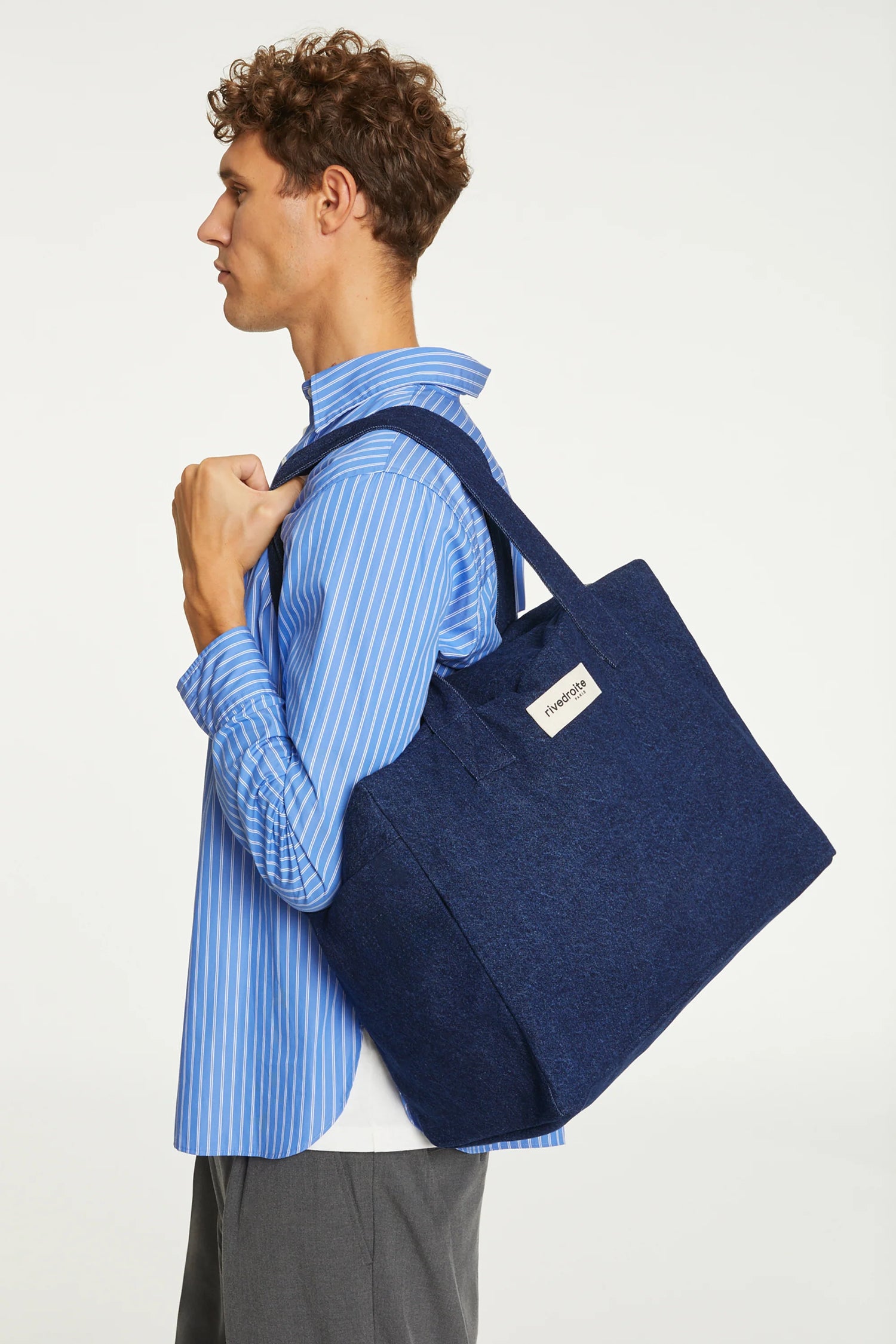 Man carrying a blue tote bag on a white background