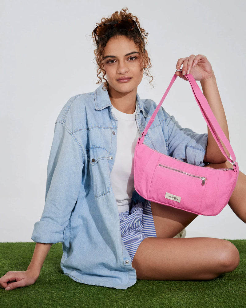 Woman holding a pink handbag on a grassy surface with a white background