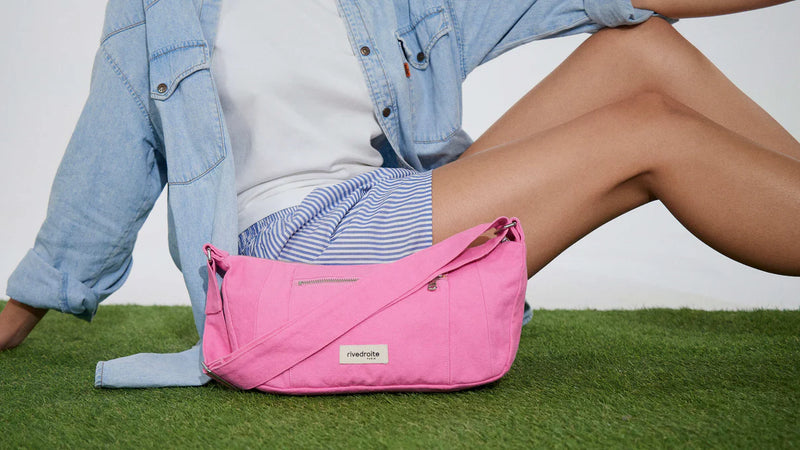 Person wearing a pink bag with a visible brand logo on grass.