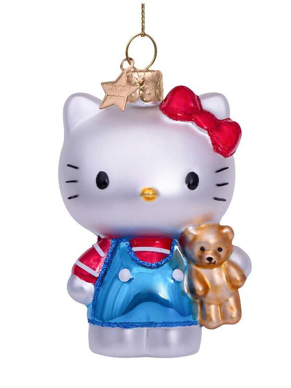 Decorative ornament of a white cat with a red bow, blue dress, and holding a teddy bear on a white background.