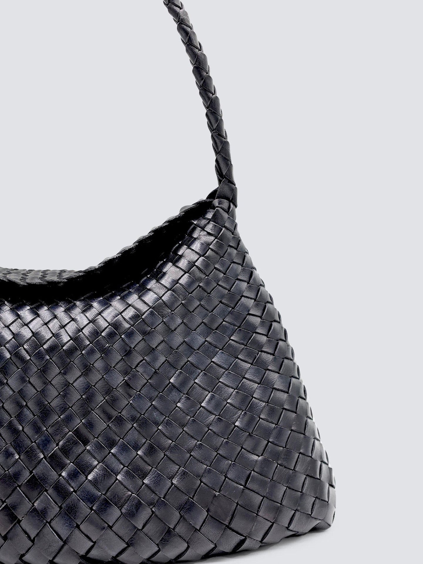 Black woven handbag on a light gray background