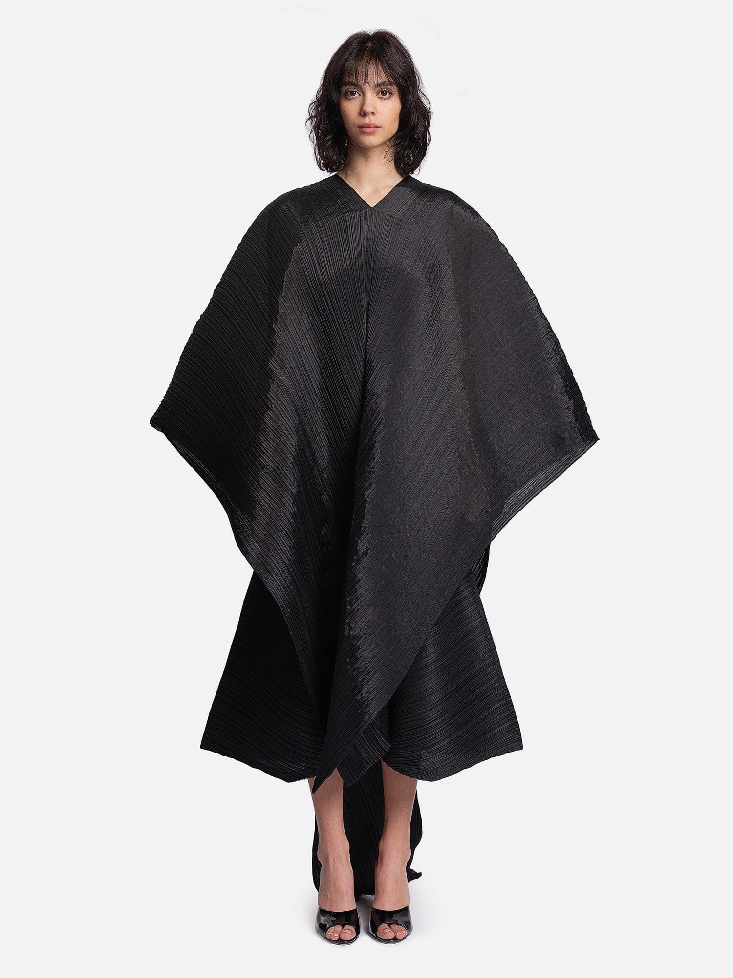 Woman wearing a black poncho against a white background