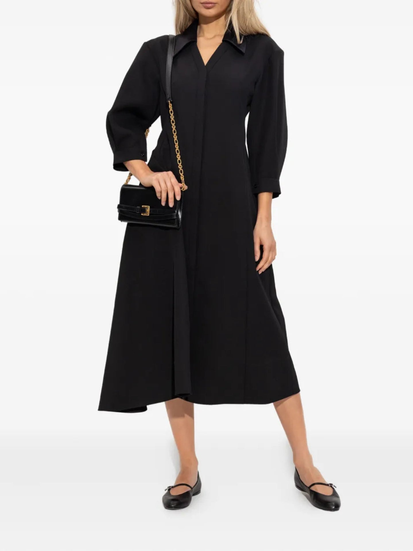 Woman wearing a black dress holding a black handbag on a white background