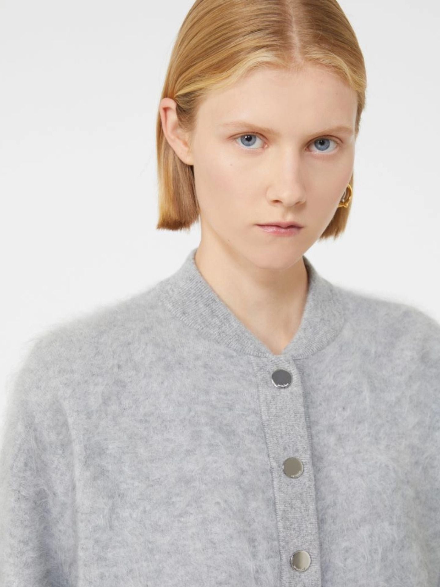 Person wearing a gray button-up shirt against a white background