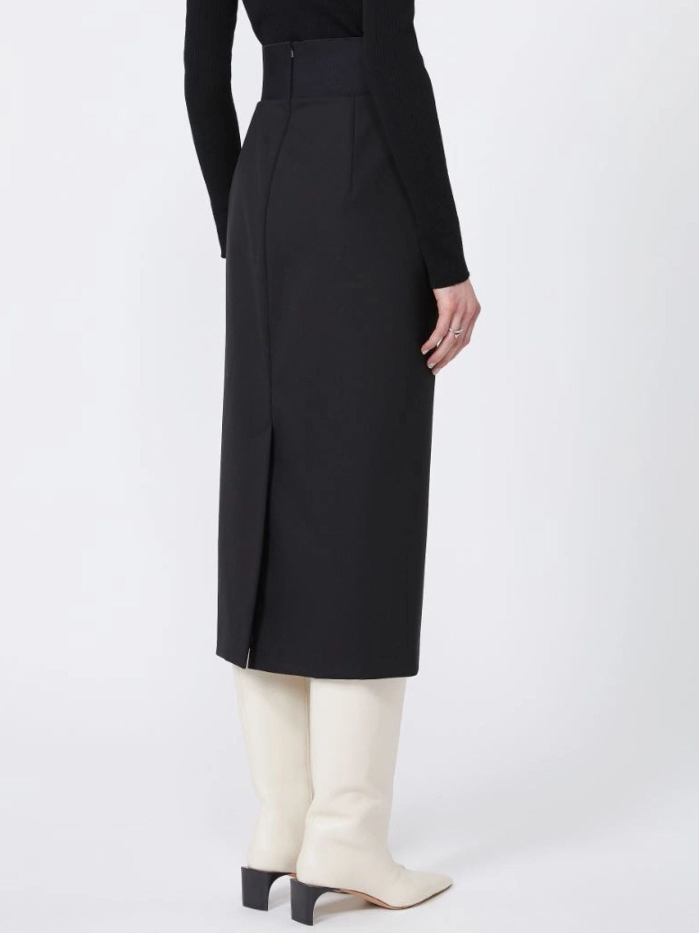 Person wearing a black skirt with white boots on a white background