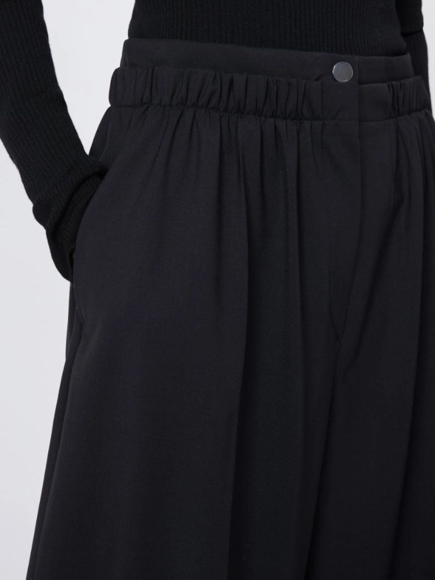 Black pants with a close-up on the waistband against a light gray background