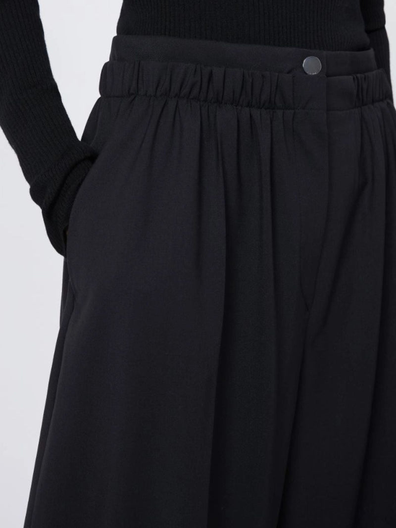 Black pants with a close-up on the waistband against a light gray background