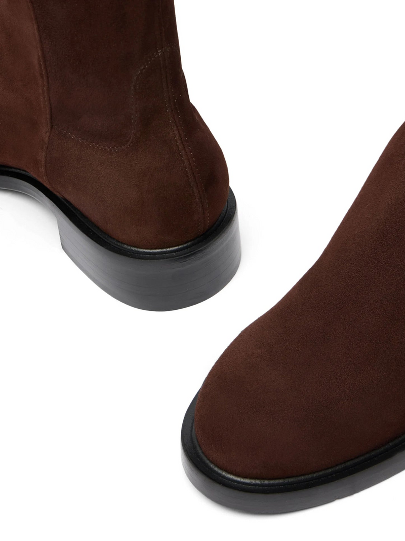 Brown suede boots with black soles on a white background