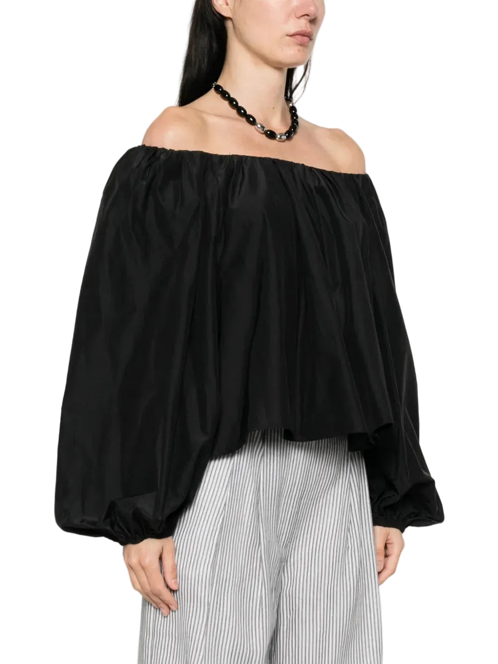 Black off-shoulder top worn by a person on a white background
