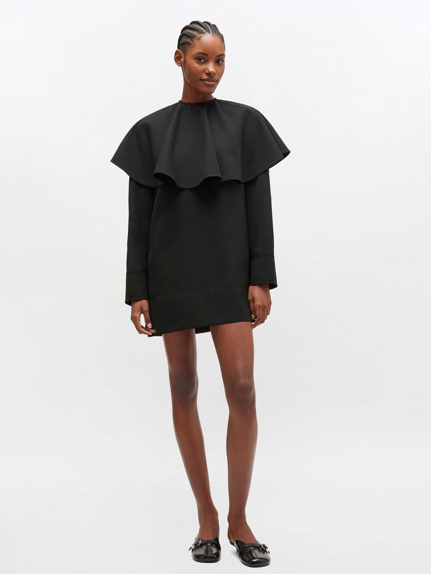 Woman wearing a black dress with ruffled collar on a white background