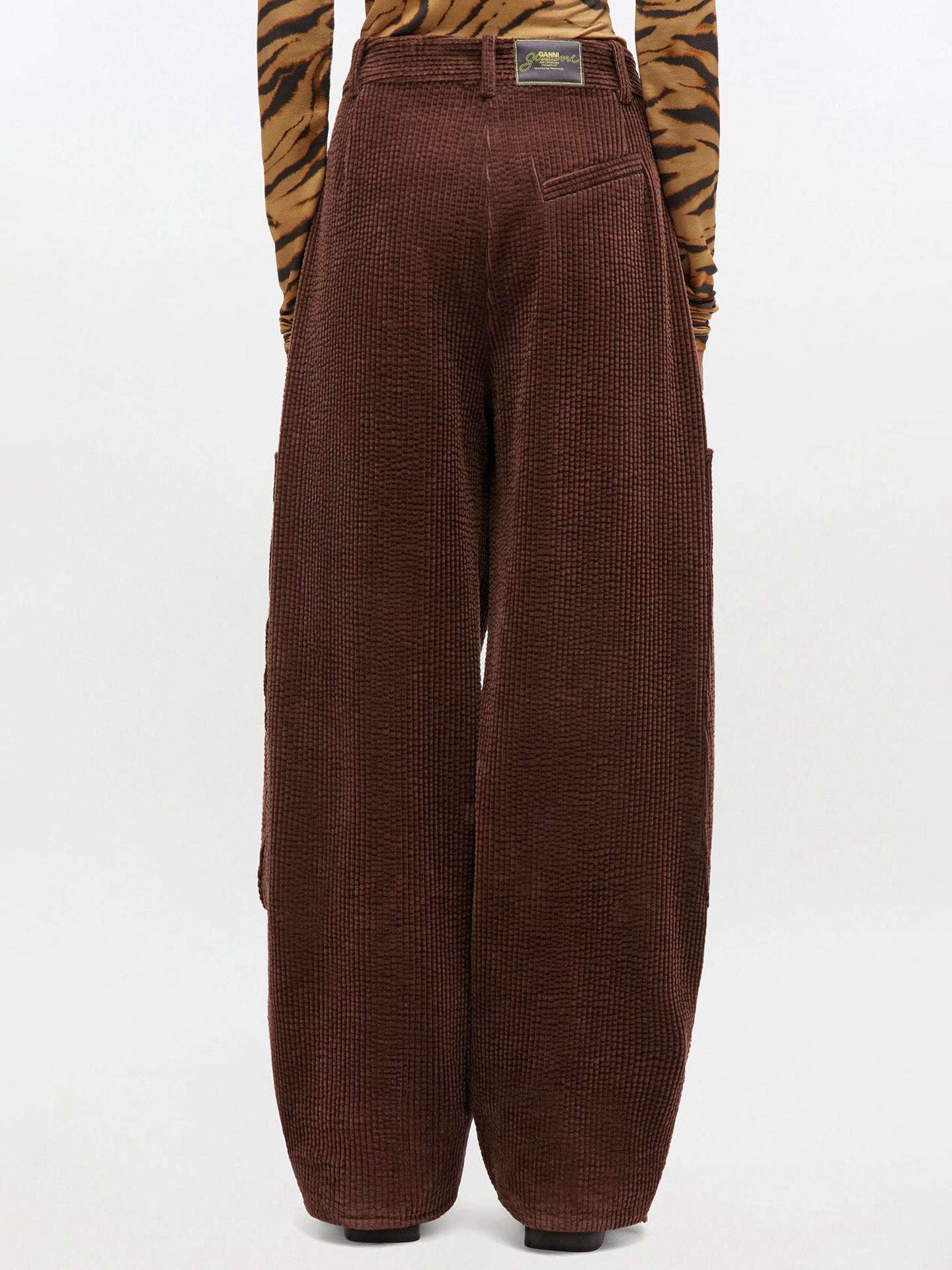 Brown corduroy pants worn with a tiger print top on a white background