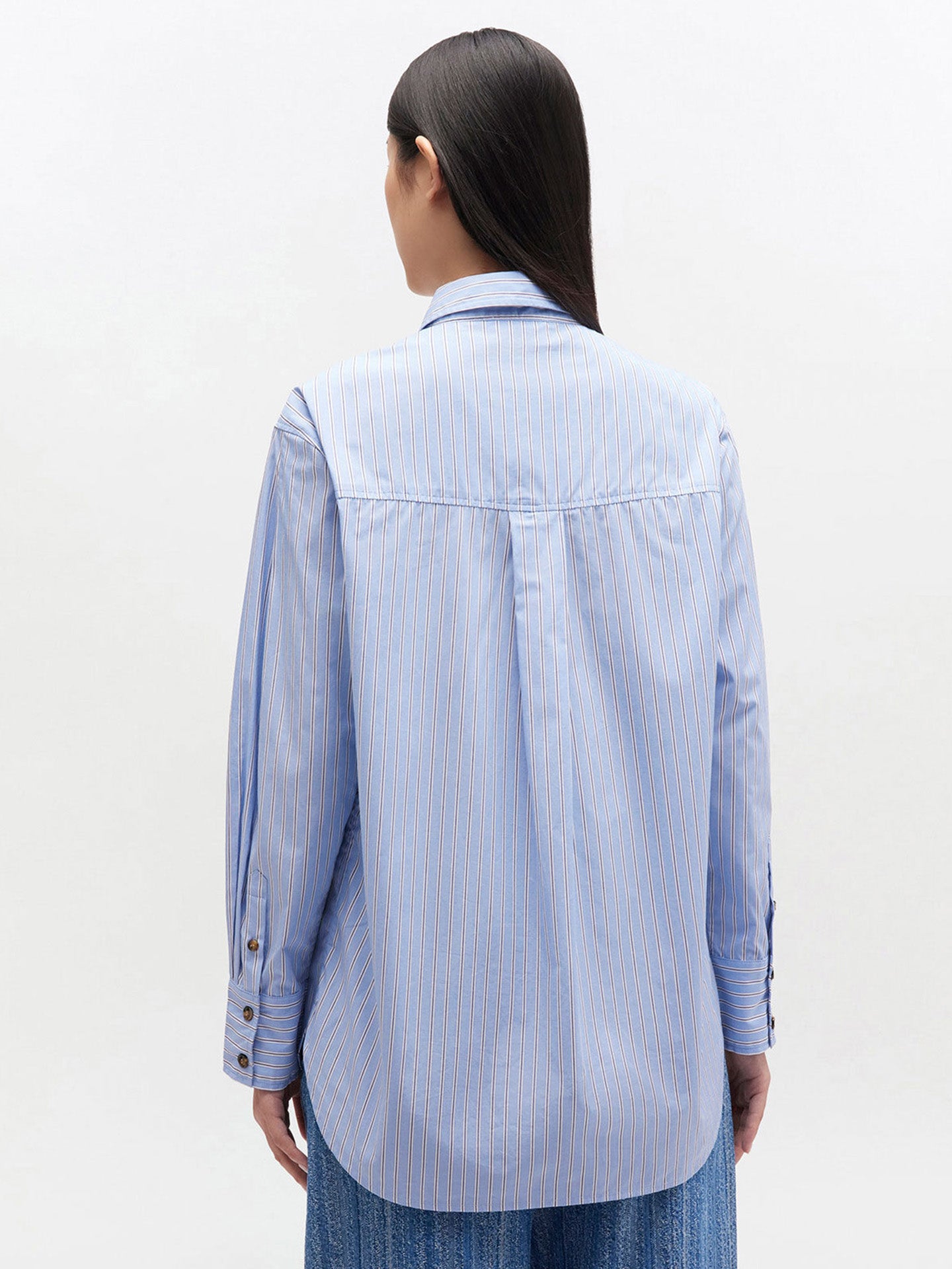 Person wearing a light blue striped shirt on a white background