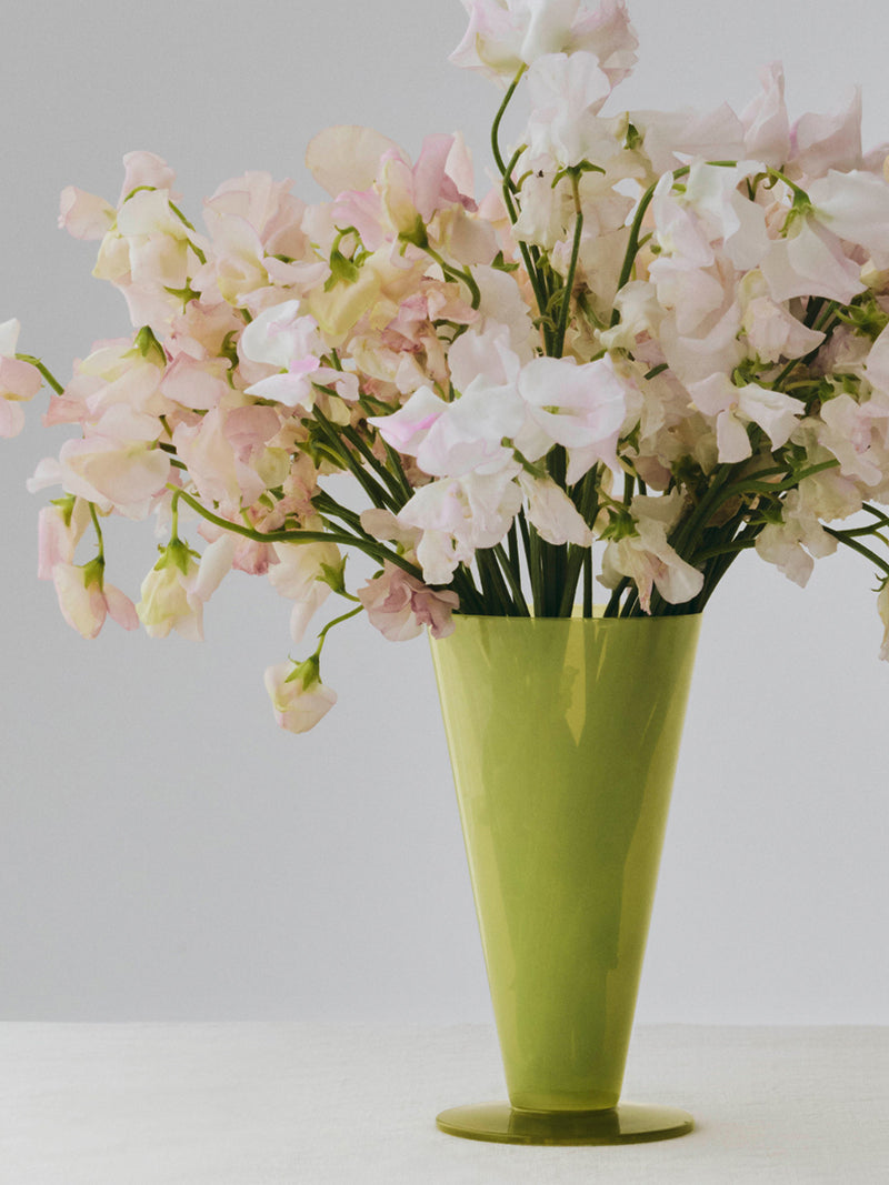Green vase with pink flowers on a white background