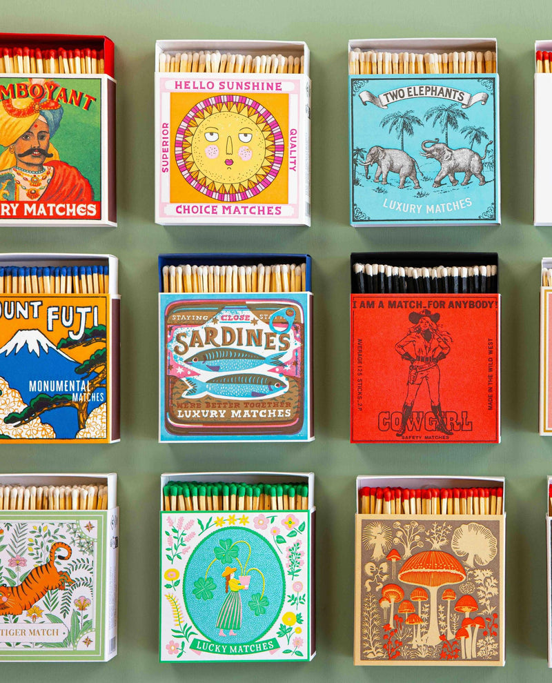 Collection of matchboxes with various designs and colors on a green background