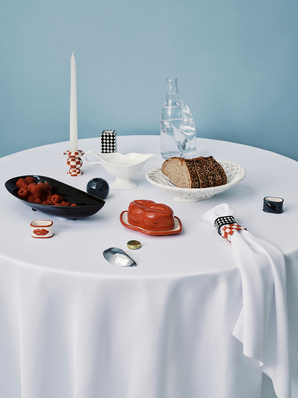 Table setting with various dishes and a candle on a light blue background