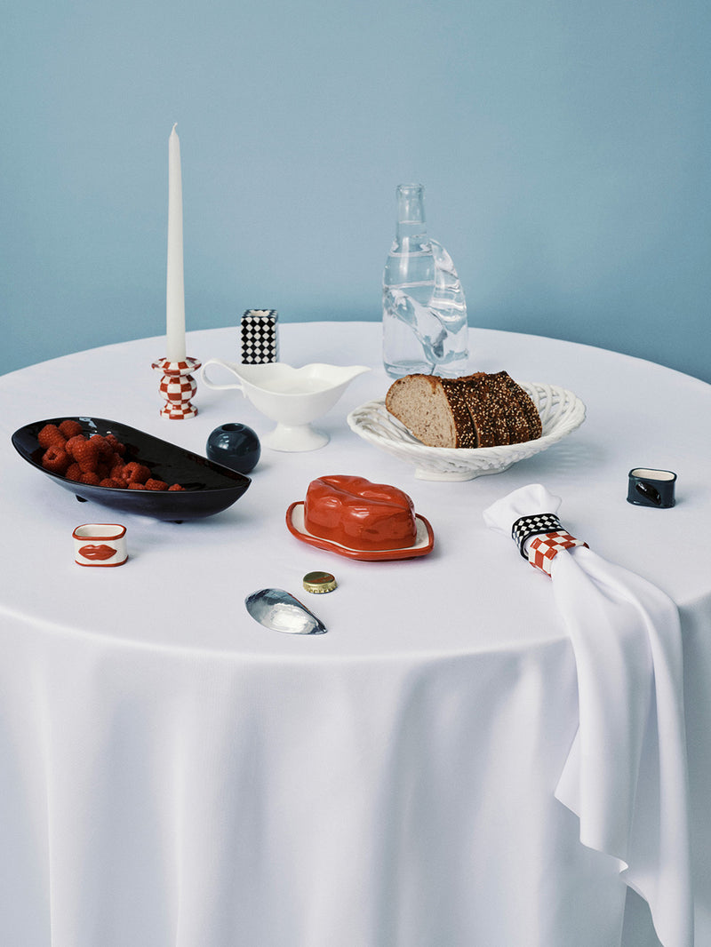 Table setting with various dishes and a candle on a light blue background