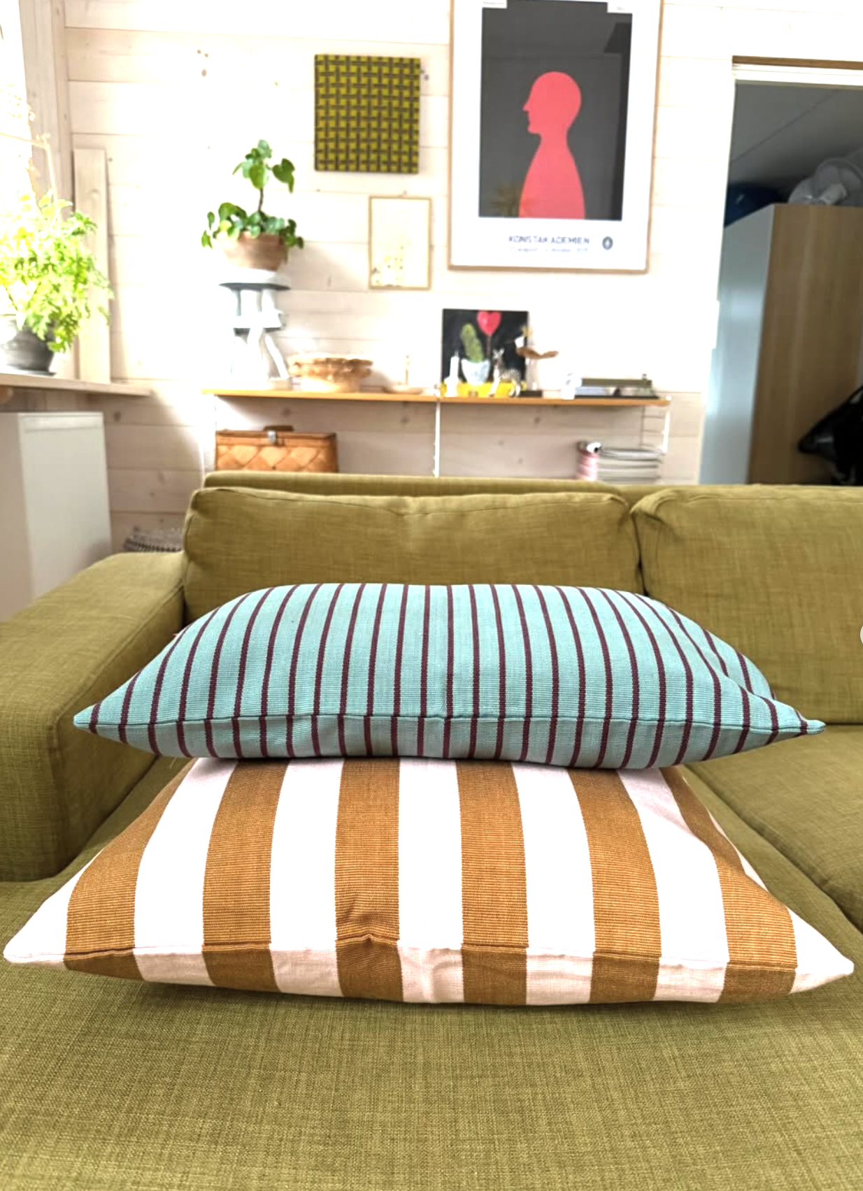 Green sofa with striped cushions in a living room setting